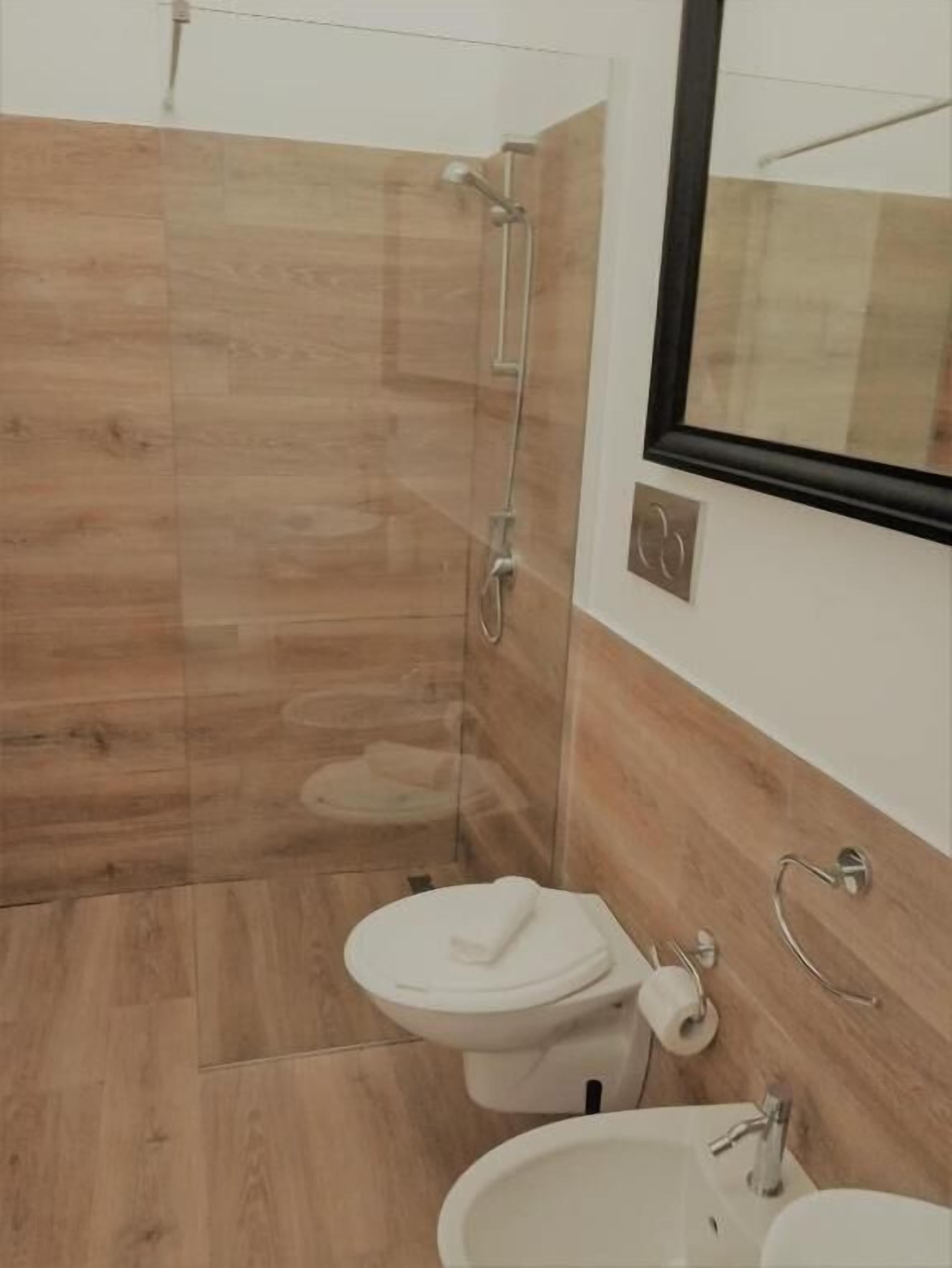 Ein modernes Badezimmer mit Duschkabine aus Glas, Toilette, Bidet und Waschbecken.