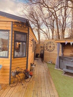 A wooden cabin with a deck, a bicycle, and a hot tub. - A Beautiful, Unique Lodge, Made for two (Lampeter)