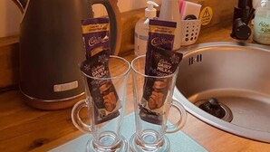 Eine Küche mit Fenster, einem Wasserkocher, zwei Gläsern mit Schokolade, einer Seifenspender und einem Warnschild.