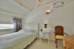 A bedroom with a single bed, a nightstand, a chair, and a window with curtains.