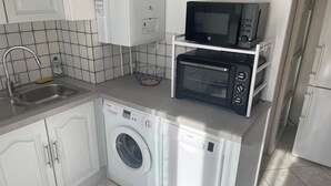 Eine kleine Küche mit Waschmaschine, Mikrowelle und Spüle.