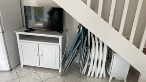Ein weißes Schränkchen mit einem Flachbildfernseher, einer Treppe und einem Halter für Reinigungsmittel.