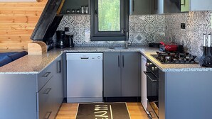 Een moderne keuken met grijze kastjes, een inbouwvaatwasser en een raam met uitzicht op groen.
