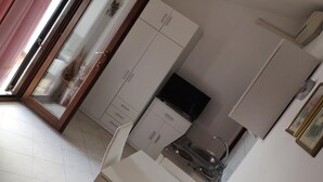 Una cocina compacta con armarios blancos, estufa integrada y un lavamanos pequeño.