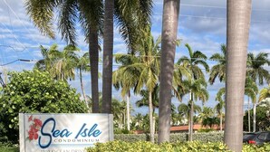 Une enseigne indiquant « Sea Isle Condominium », avec une haie verdoyante en premier plan.
