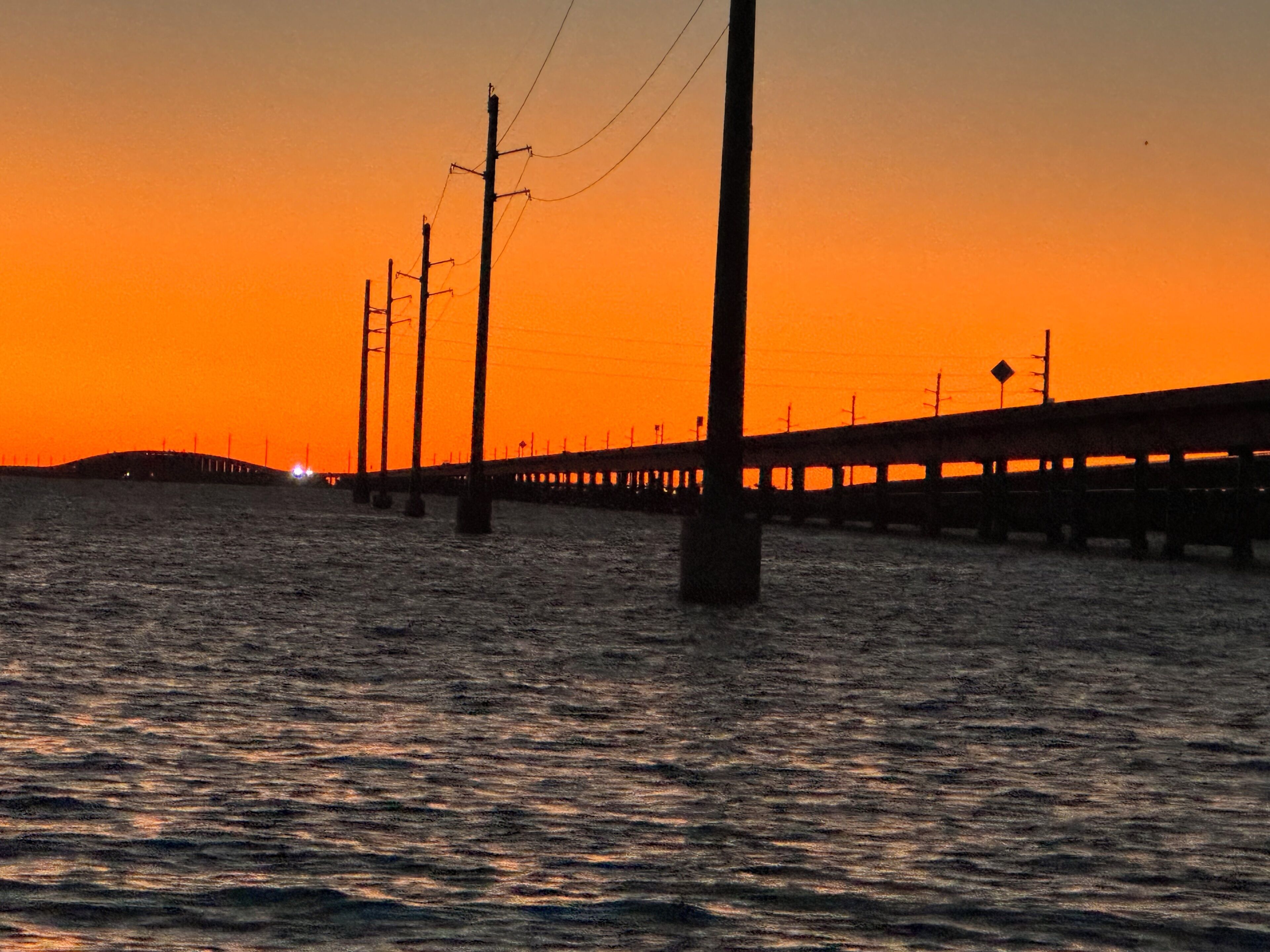A pier extending into a body of water during sunset.