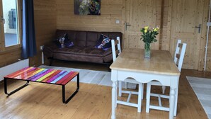 Um quarto aconchegante com um sofá de couro marrom, uma mesa branca e uma mesa com padrão listrado colorido.
