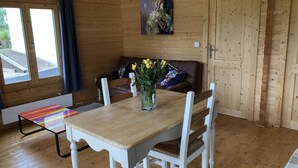 Um interior em madeira com uma mesa de jantar, cadeiras, um sofá e um quadro na parede.