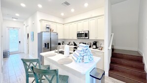A modern kitchen with white cabinets, stainless steel appliances, and a central island with seating. - 5br/5ba/5mi Disney • Heated Pool/SPA • Free Uber rides to parks! (Kissimmee)