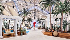 A spacious indoor atrium with a high ceiling, palm trees, and a central fountain.