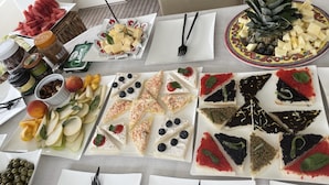 Ein Tisch mit verschiedenen Speisen, darunter Obst, Käse und Gebäck.