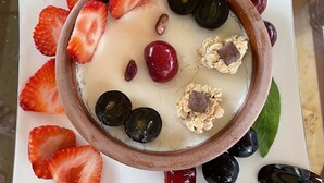 Eine Dessertschale mit Erdbeeren, Kirschen und Schokolade auf einem weißen Teller.