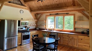 A wooden interior with a kitchen, dining area, and a staircase. - Post and Beam Carriage House in the heart of Mad River Valley (Waitsfield)