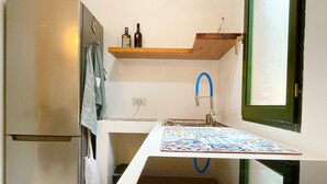 Una cocina compacta con refrigerador, pileta y ventana.