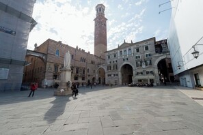A historic square with a prominent tower, stone buildings, and a fountain.
