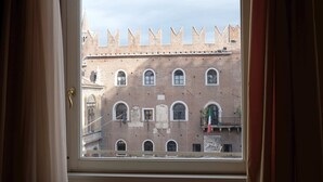 A view through a window of a historic building with a crenellated tower and arched windows. - Domus Nova - Three Bedroom Apartment, Sleeps 6 (Verona)