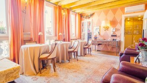A dining area with round tables and chairs, a desk with a telephone, and a vase with flowers. - Domus Nova - Three Bedroom Apartment, Sleeps 6 (Verona)