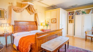A bedroom with a wooden bed, bedside table, bench, and a bookshelf with books and decorative items. - Domus Nova - Three Bedroom Apartment, Sleeps 6 (Verona)