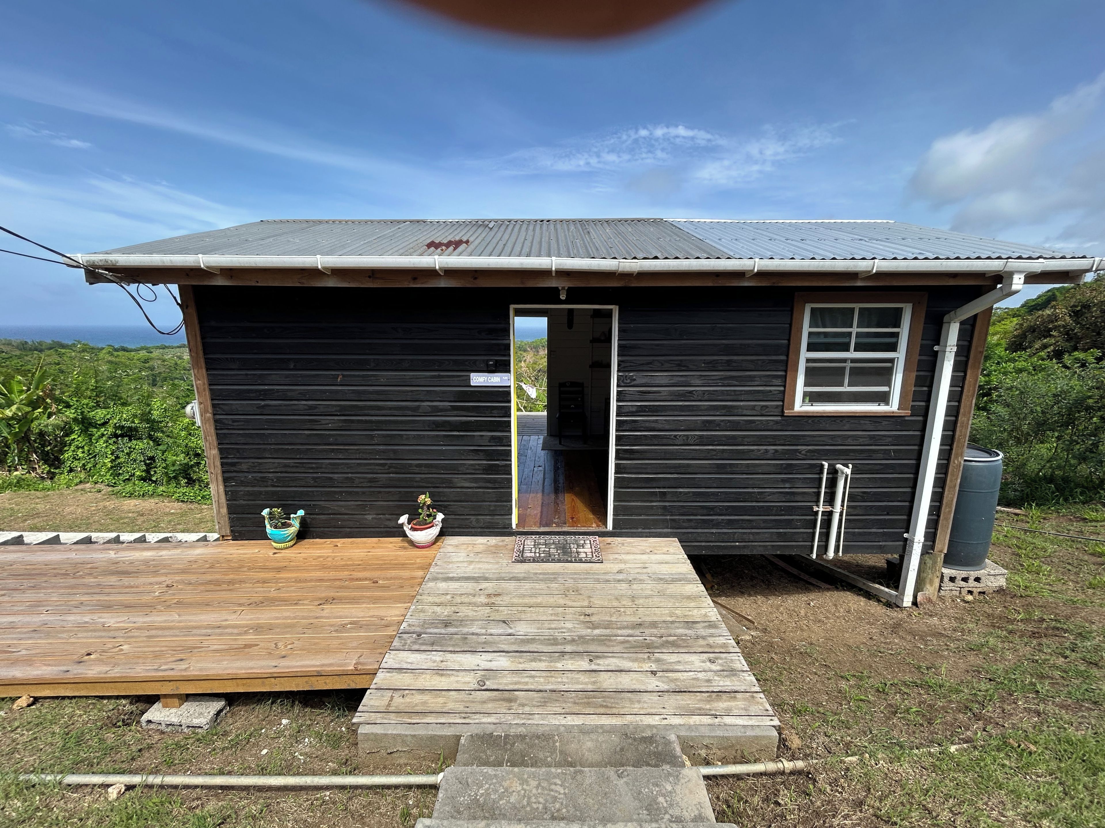A small black cabin with a wooden deck, a window, and a door.