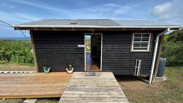 A small black cabin with a wooden deck, a window, and a door.