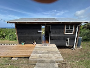 A small black cabin with a wooden deck, a window, and a door.