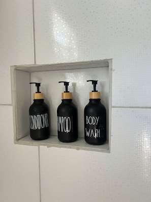 A bathroom shelf with three black bottles labeled conditioner, shampoo, and body wash. - ComfyCabin is rustic with modern amenities, has deck with great view. Peaceful. (Mount Rose)