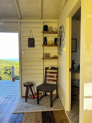 A wooden interior with a chair, a small table, and a shelf with decorative items.