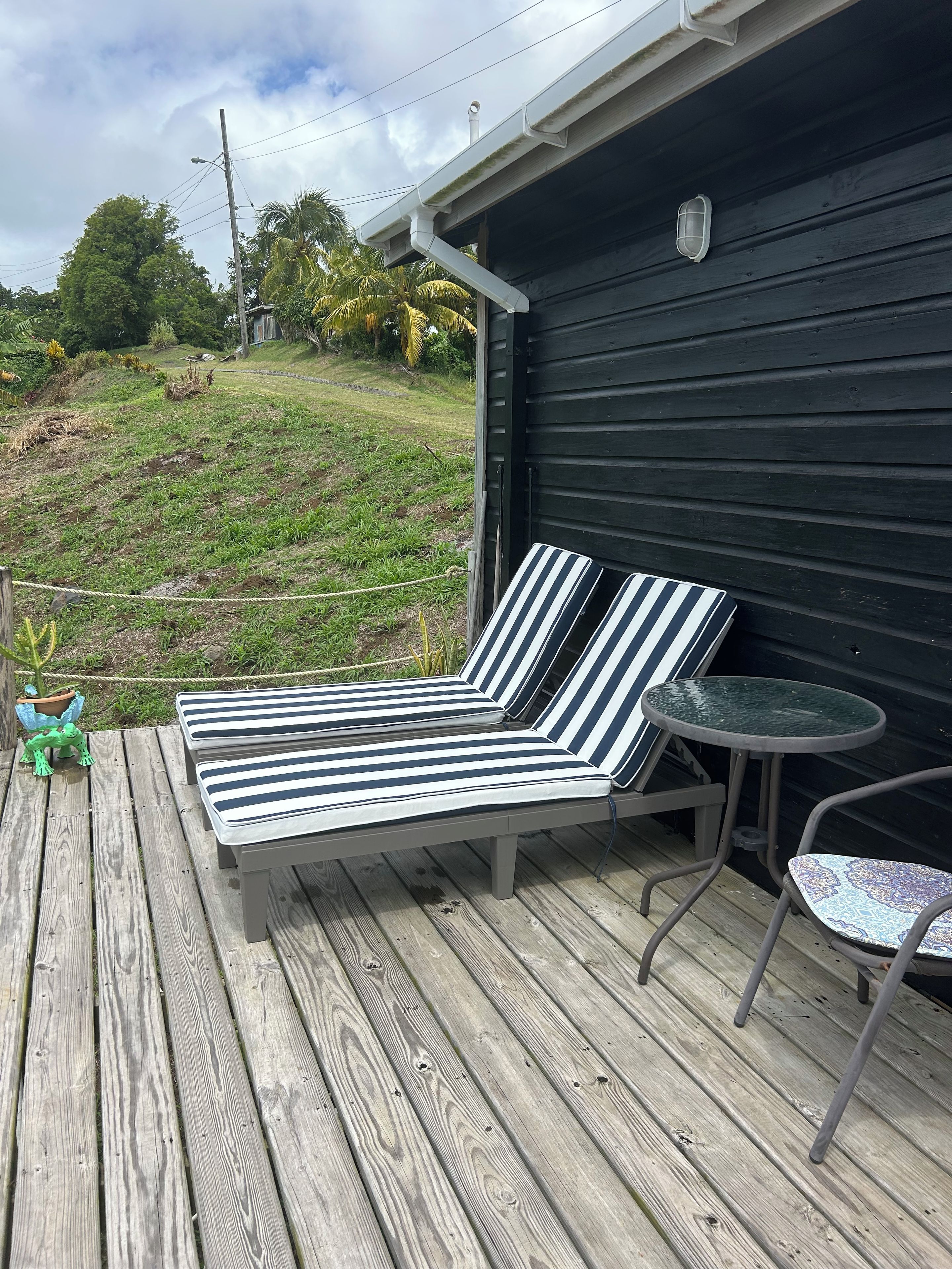 Una terraza de madera con una silla de descanso y una mesita.