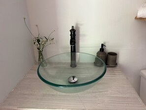 A bathroom with a glass bowl sink, a black faucet, a vase with white flowers, and a soap dispenser. - ComfyCabin is rustic with modern amenities, has deck with great view. Peaceful. (Mount Rose)