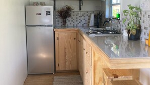 Een kleine keuken met houten kastjes, een inbouwkoelkast, een klein spoelgedeelte en een houten kookeiland met krukken.
