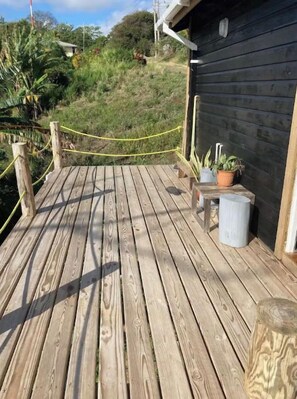 Une terrasse en bois avec une barrière en corde, des plantes en pot et un bâtiment en arrière-plan.