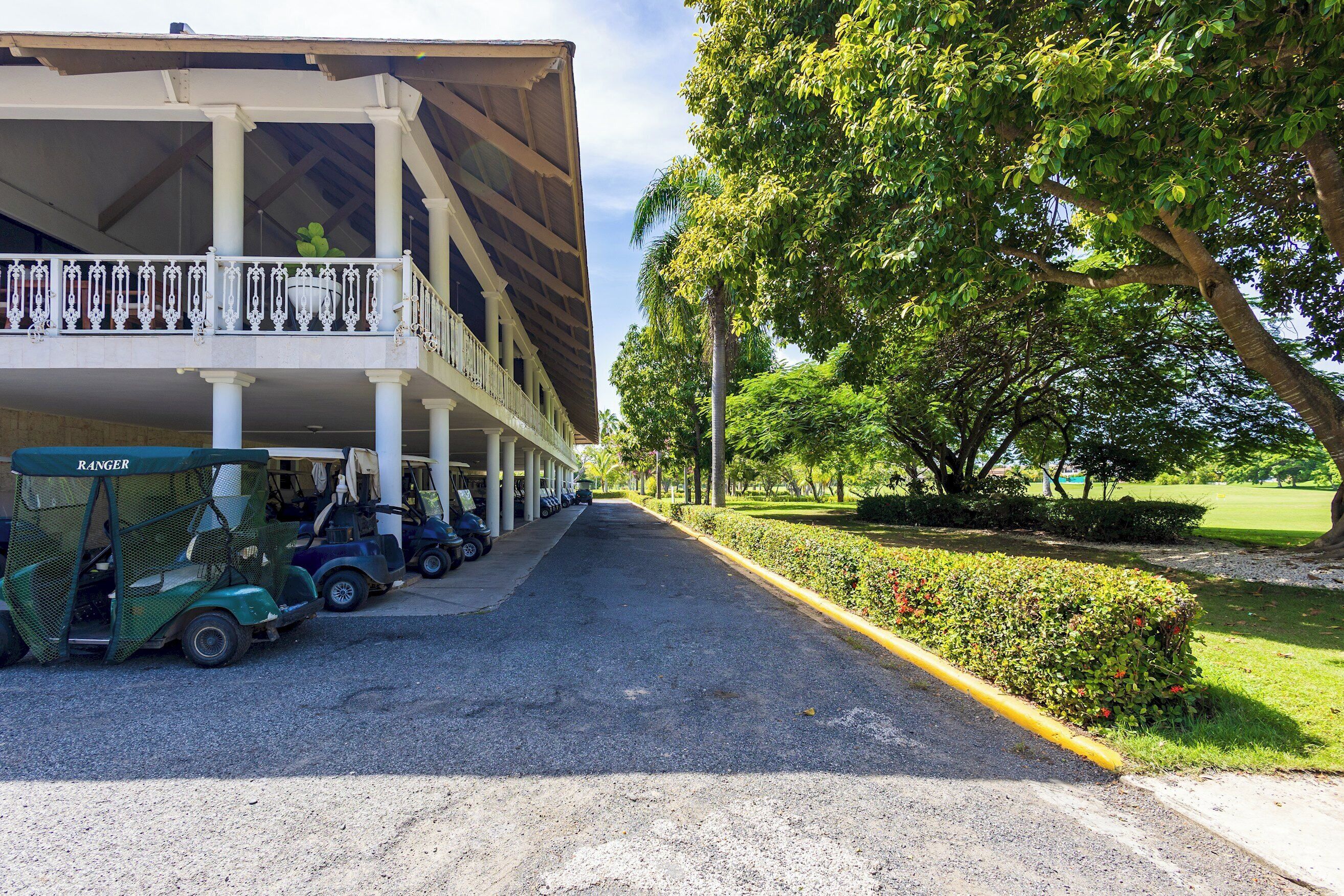 A building with a covered outdoor area and a row of golf carts parked in front.