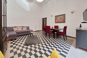 A living room with a checkered floor, a sofa, a dining table with chairs, and a TV.