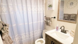 A bathroom with a toilet, sink, and shower curtain. - Pet Friendly! Private Casita in Nob Hill (Albuquerque)