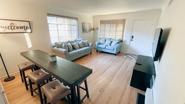 A modern living room with a dining area, a sofa, a coffee table, and a TV. - Pet Friendly! Private Casita in Nob Hill (Albuquerque)
