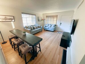 Een moderne woonkamer met een eethoek, een bank, een salontafel en een televisie.