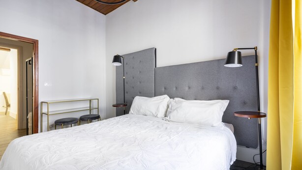 Una habitación de hotel moderna con una cama grande, dos mesitas de noche y dos lámparas de pie.