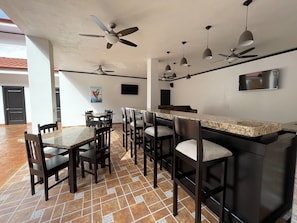 Une cuisine moderne dotée d’un bar, de plusieurs ventilateurs de plafond et d’un sol carrelé.