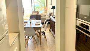 A modern kitchen with white cabinets, a Bosch refrigerator, and a dining area with a table and chairs. - NEW APARTAMENT WITH LARGE TERRACE JUST ON THE BEACH W/ FAST  INTERNET (Almuñécar)