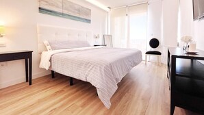 A modern bedroom with a large bed, a bedside table, a chair, and a desk. - NEW APARTAMENT WITH LARGE TERRACE JUST ON THE BEACH W/ FAST  INTERNET (Almuñécar)