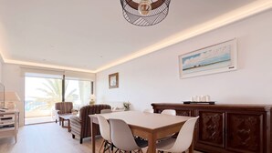 A spacious dining area with a wooden table and chairs, a large window with a view of the sea, and a ceiling light fixture. - NEW APARTAMENT WITH LARGE TERRACE JUST ON THE BEACH W/ FAST  INTERNET (Almuñécar)