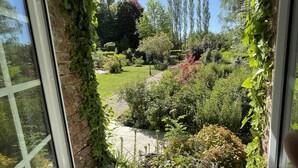 A window with a view of a garden, a brick wall, and a clear blue sky. - la Fontaine Romy (Genneville)