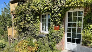 A rustic house with a thatched roof, ivy-covered walls, and a stone pathway leading to the entrance. - la Fontaine Romy (Genneville)