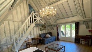 A spacious loft bedroom with a large bed, a glass coffee table, a sofa, and a staircase leading to an upper level. - la Fontaine Romy (Genneville)