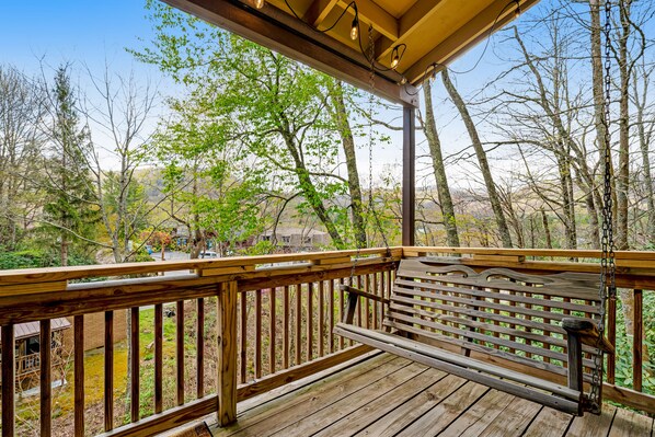 Relax on the deck with a hanging swing, taking in the serene views of the surrounding trees and residential area.