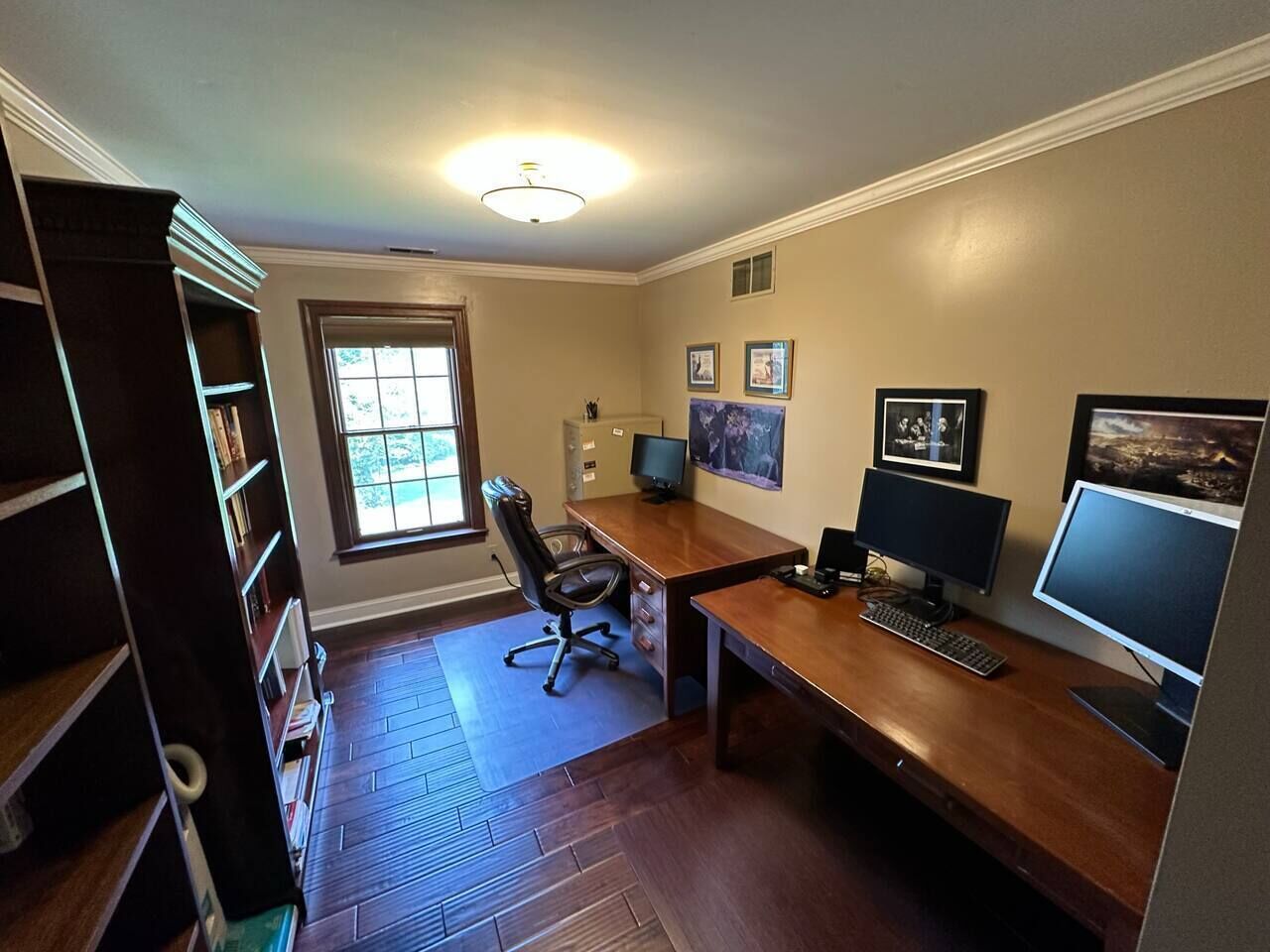 Ein Homeoffice mit Schreibtisch, zwei Monitoren, einem Stuhl und einem Bücherregal.