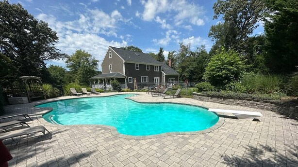 A swimming pool with lounge chairs, a brick patio, and a house in the background. - Large Home w/ Private Pool, Gym, Sauna, 7 Bedrooms, Sleeps 21 (Severn)