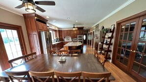 A spacious kitchen with wooden cabinets, a large island, and a dining area with wooden chairs. - Large Home w/ Private Pool, Gym, Sauna, 7 Bedrooms, Sleeps 21 (Severn)