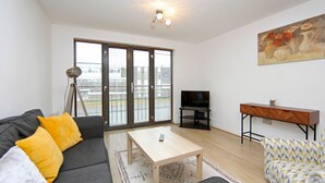 A modern living room with a sofa, a coffee table, a TV, and a painting on the wall. - Albion Street Apartments (Wolverhampton)