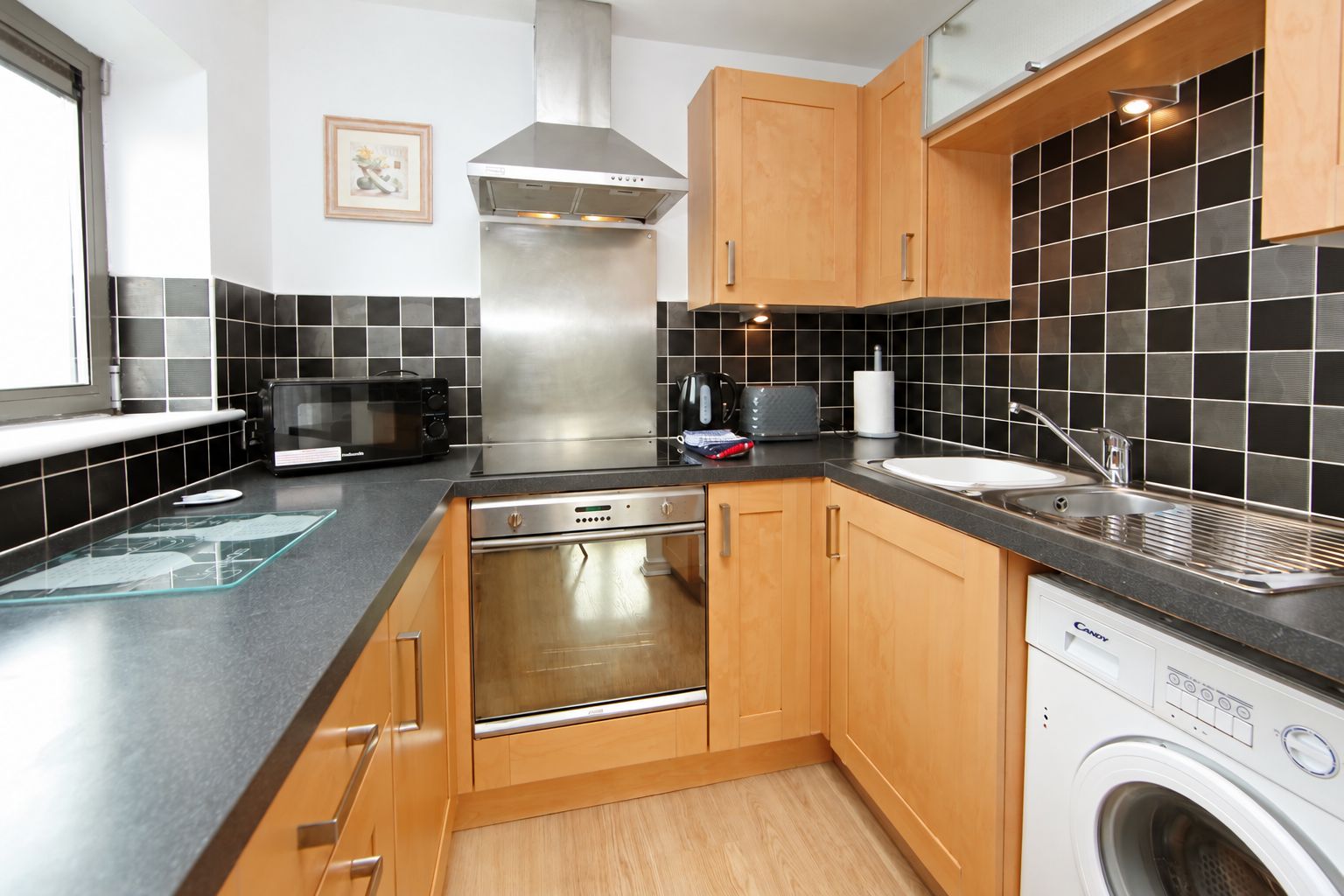A compact kitchen with a dishwasher, microwave, and a built-in oven.